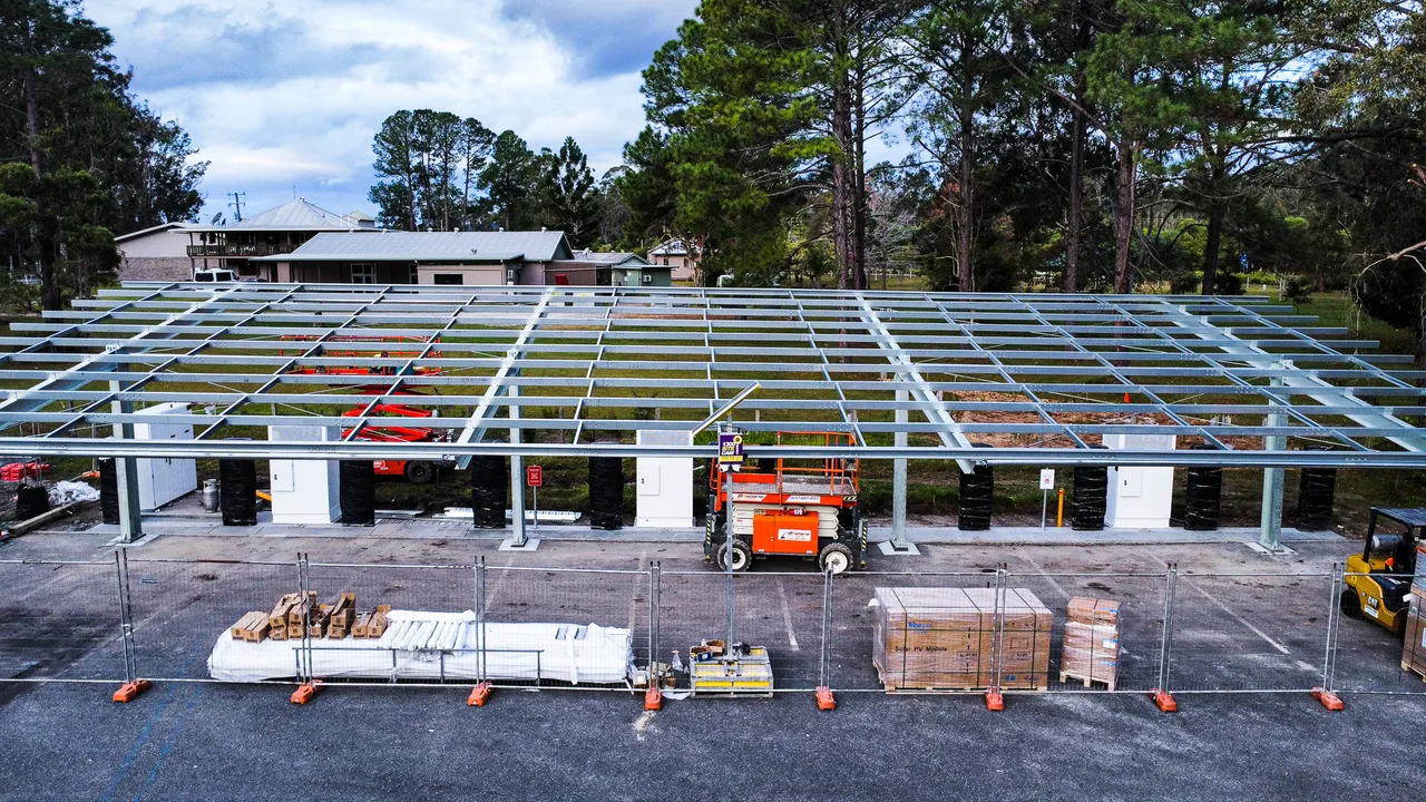 Luchtfoto van de bouw van een grootschalige commerciële solar carport op een parkeerterrein