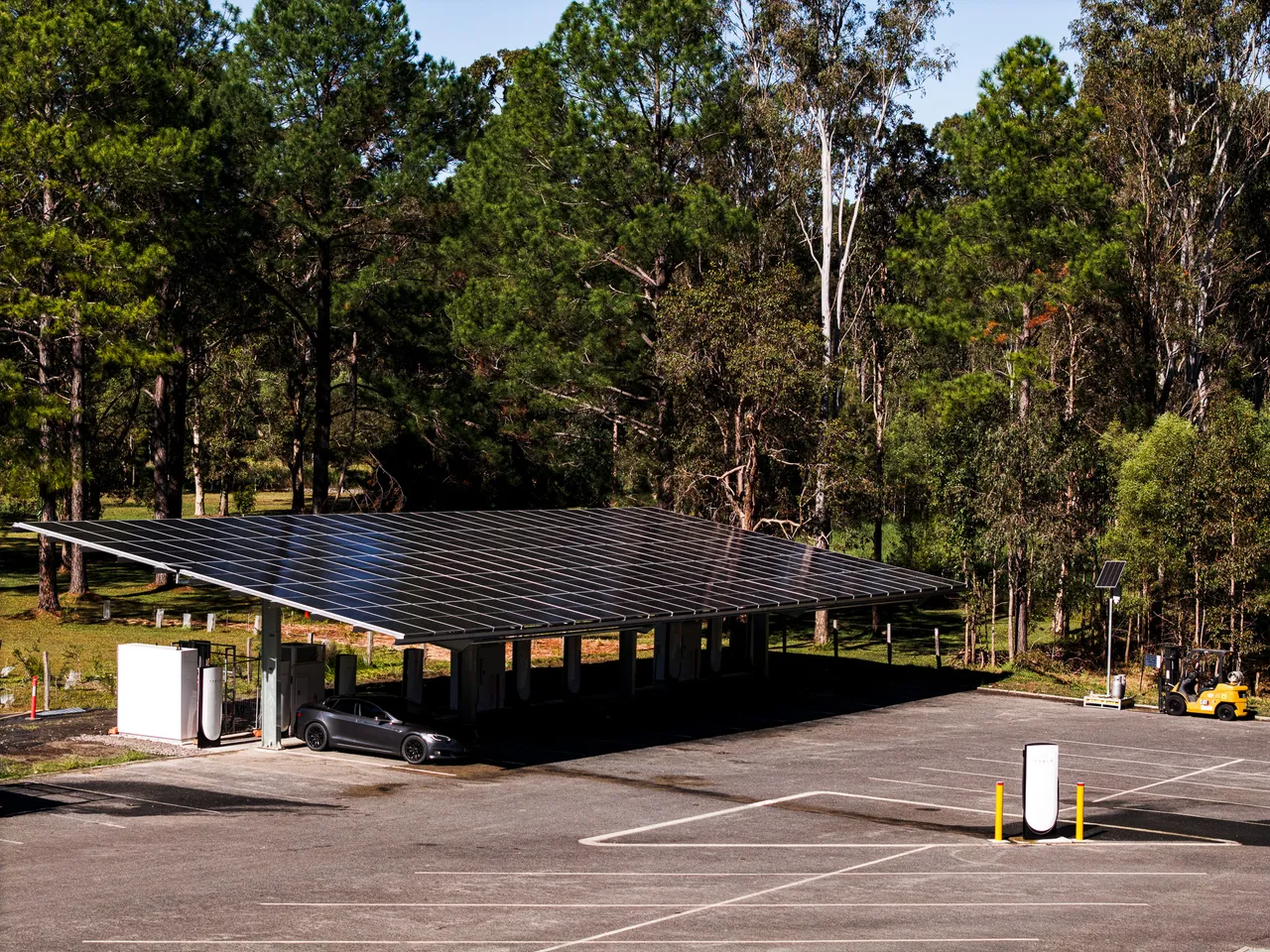 Commerciële solar carport met Tesla bij laadstation en zonnepanelen