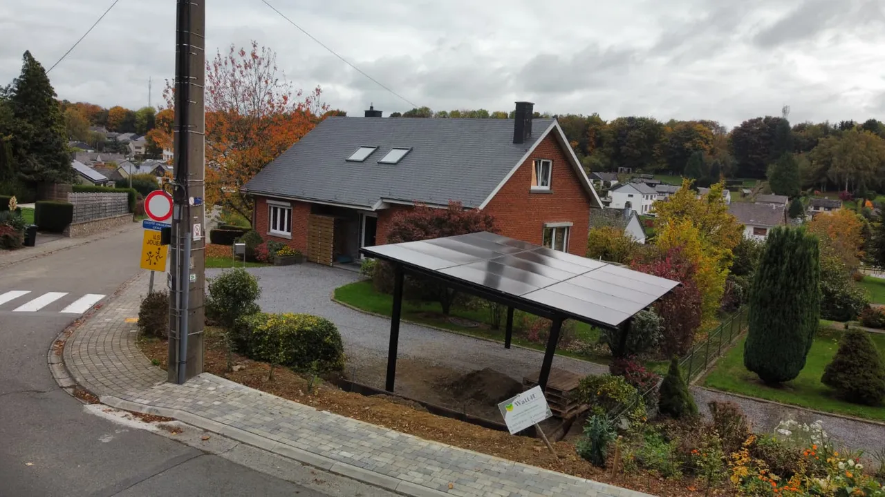 Solar carport geïnstalleerd op de oprit van een bakstenen woning, bovenaanzicht