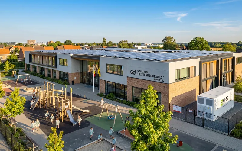 Batterijopslag BESS voor scholen en gemeenten - schoolgebouw met groot plat dak vol zonnepanelen en speelplaats